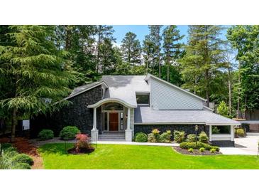 Striking exterior of a home with stone accents, gray siding, and a manicured lawn surrounded by mature trees at 4070 Whitewater Creek Rd, Atlanta, GA 30327