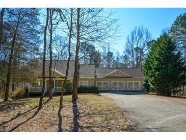 Traditional home showing attached three-car garage and covered porch with neutral siding and dark-stained trim at 6865 Cowan Mill Rd, Winston, GA 30187