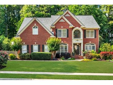 Charming brick home featuring lush landscaping, a manicured lawn, and a welcoming front entrance at 660 Briarleigh Way, Woodstock, GA 30189
