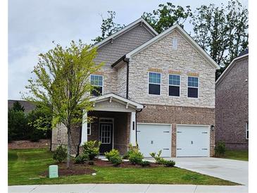 Charming two-story home with a stone and brick facade, a well-manicured lawn, and a two-car garage at 1961 Ecoland Dr, Grayson, GA 30017