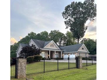 Charming brick home features a well-manicured front yard and a black wrought iron fence at 4829 Moon Rd, Powder Springs, GA 30127