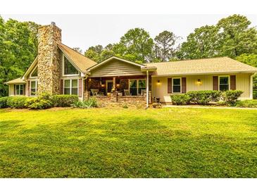 Charming ranch-style home with a stone chimney, inviting front porch, and lush green lawn at 130 Brooklet Way, Brooks, GA 30205