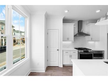 Bright kitchen features white cabinets, stainless steel appliances, subway tile backsplash, and a large window at 628 Skytop Dr # 158, Cumming, GA 30040