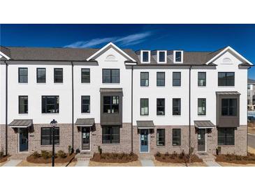 Modern townhome exterior showcases white brick, multiple windows, and stylish architectural details at 621 Silva St # 124, Cumming, GA 30040