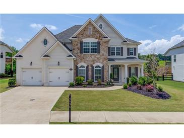 Beautiful two-story home with a well-manicured lawn, stone accents, and a three-car garage at 4035 Starwood Dr, Cumming, GA 30028