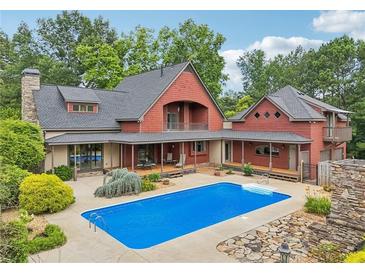 Stunning exterior view of the home with a beautiful pool and a patio area, surrounded by lush greenery at 150 Henderson Farm Dr, Woodstock, GA 30188