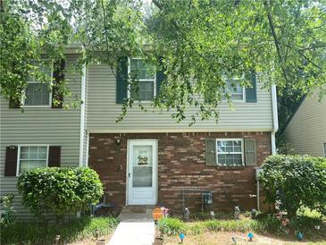 Charming townhome featuring a brick facade, complemented by well-manicured landscaping and leafy trees at 8959 Stonebridge Blvd, Douglasville, GA 30134