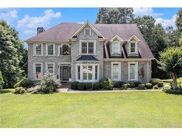 Charming two-story home with stone facade, mature trees, and well-manicured lawn at 317 Saint Pauls Ct, Stockbridge, GA 30281