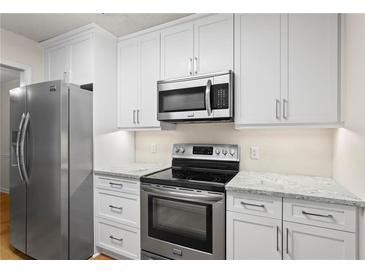 Well-lit kitchen featuring stainless steel appliances, white cabinets, and granite countertops at 111 Abingdon Way, Sandy Springs, GA 30328