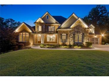Beautiful two-story brick home with manicured lawn, professional landscaping, and elegant lighting at 5114 Brendlynn Dr, Suwanee, GA 30024