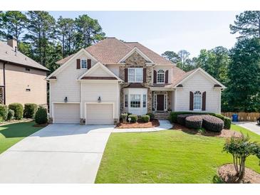 Charming two-story home with a manicured front yard, three-car garage, stone accents, and covered entrance at 4171 Lantern Hill Dr, Dacula, GA 30019