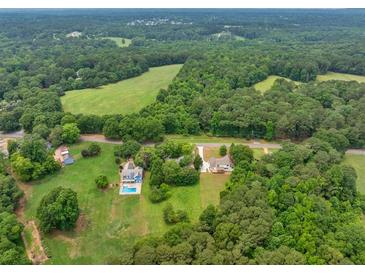 A beautiful aerial view of a home surrounded by lush greenery and a nearby meadow, creating a serene and private setting at 4444 Cannon Sw Rd, Loganville, GA 30052