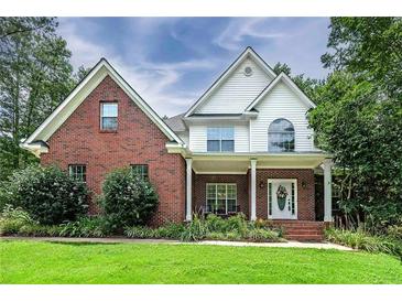 Charming brick and siding home with covered front porch and well-maintained landscaping at 90 Barrington Grange Dr, Sharpsburg, GA 30277