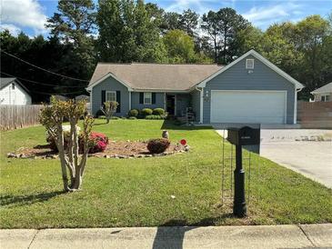 Charming single-story home featuring a well-manicured front yard with mature trees, flowerbeds and an attached two-car garage at 1109 Granite Ln, Loganville, GA 30052