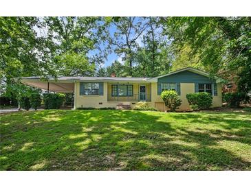 Charming one-story home with yellow brick, blue trim, mature trees, and a well-manicured lawn at 1729 Norden Rd, Riverdale, GA 30296