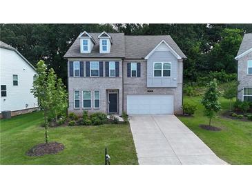 Charming two-story home featuring gray brick, a two-car garage, manicured lawn and a welcoming front porch at 5090 Bellehurst Ln, Cumming, GA 30040