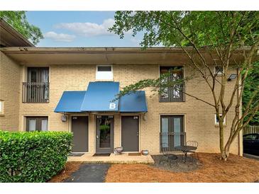 Charming townhouse exterior with brick facade, blue awnings, and manicured landscaping at 2023 Oakview Se Rd # 226, Atlanta, GA 30317