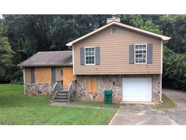 Two-story home with stone accents, wood siding, and some boarded up windows at 3778 Glen Mora Dr, Decatur, GA 30032