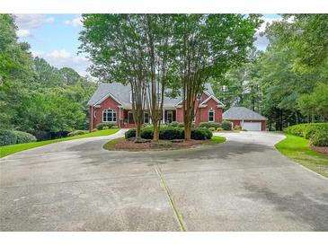 Stately brick home with a circular driveway, mature landscaping, and attached garage nestled on a wooded lot at 750 Old Loganville Road Southwest, Loganville, GA 30052