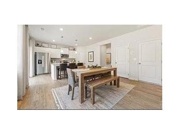 Bright dining area featuring a modern table with bench seating adjacent to a stainless steel kitchen and hardwood flooring at 8504 Polston Lot 145 Pl, Douglasville, GA 30134