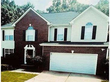 Charming two-story home with brick and vinyl siding, a well-manicured lawn, and an attached two-car garage at 3233 Rockmill Dr, Ellenwood, GA 30294