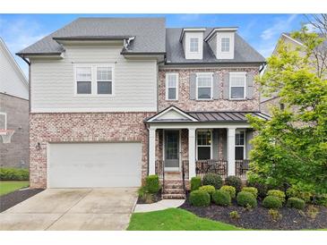 Charming two-story home features a mix of brick and siding, a welcoming front porch, and a well-manicured lawn at 4130 Millbrook Ct, Suwanee, GA 30024