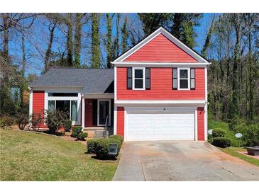 Charming red two-story home with a well-manicured lawn and two-car garage at 7472 Woods Ct, Lithonia, GA 30058