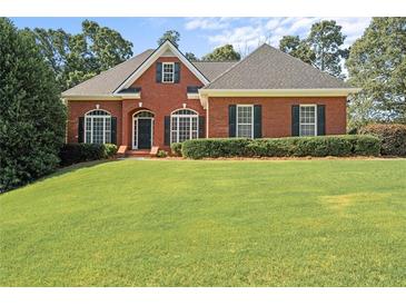 Charming single-story brick home featuring a lush green lawn, manicured shrubs, and inviting curb appeal at 5831 Wembley Dr, Douglasville, GA 30135