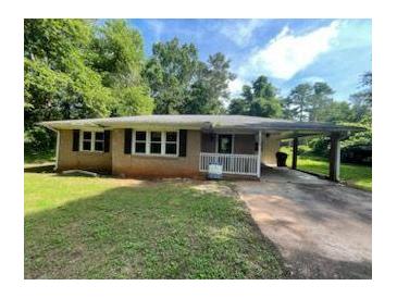 Cozy single-story home with a brick facade, large windows, and a covered carport on a partially sunny day at 2369 Christian Cir, Covington, GA 30016