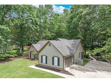 Well-maintained home featuring neutral siding, black shutters, and an attached garage in a lush, green setting at 2105 Huntington Hills Trce, Buford, GA 30519