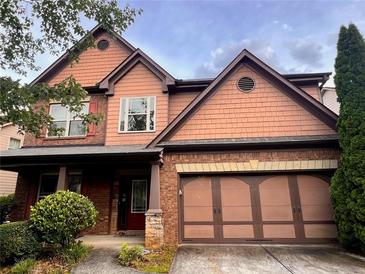 Charming two-story home with brick and shingle exterior, showcasing a well-manicured front yard and a two-car garage at 2532 Gloster Mill Drive Southwest, Lawrenceville, GA 30044