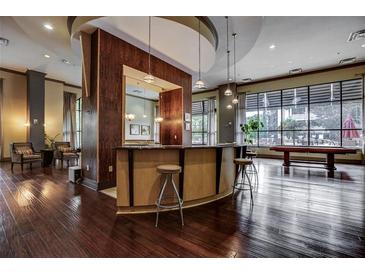 Modern lounge area featuring a bar, hardwood floors, and large windows overlooking the outdoor space at 3040 Peachtree Nw Rd # 1713, Atlanta, GA 30305