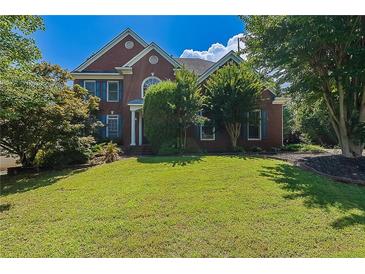 Beautiful brick home with manicured lawn, lush landscaping, and charming architectural details at 901 Chadwick Park Dr, Lawrenceville, GA 30045