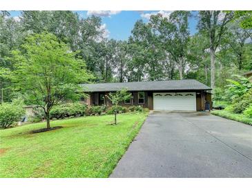 Charming ranch home with well-manicured lawn, mature trees, and long driveway leading to a two-car garage at 3229 Richwood Dr, Duluth, GA 30096