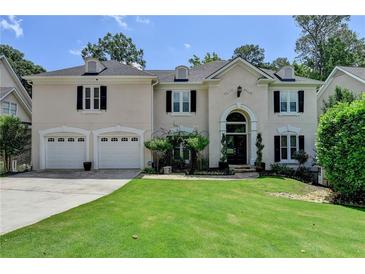 Stately home featuring a manicured lawn, arched entryway, and a convenient two-car garage at 5245 Cottage Farm Rd, Johns Creek, GA 30022