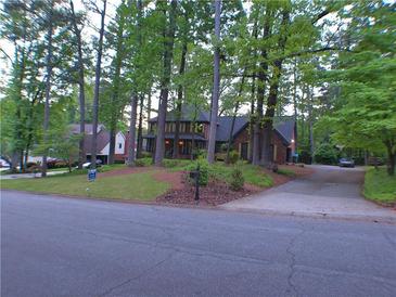 View of a red brick two-story home with manicured front yard surrounded by mature trees and bushes at 5741 Wolf Laurel Ln, Lilburn, GA 30047