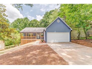 Charming blue home with a spacious front yard, inviting porch, and a convenient two-car garage at 7074 Babbling Brook Dr, Jonesboro, GA 30236