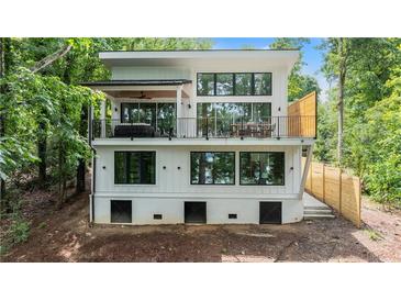 Stunning, contemporary two-story home featuring large windows and a spacious outdoor balcony overlooking the lush surroundings at 6178 Lake Lanier Height Rd, Buford, GA 30518