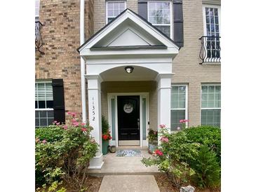 Charming home entrance with a black door, welcoming wreath, and lovely landscaping with colorful flowers at 11352 Musette Cir, Alpharetta, GA 30009