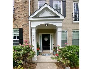 Charming front entrance with black door, white pillars, and blooming pink rose bushes at 11352 Musette Cir, Alpharetta, GA 30009