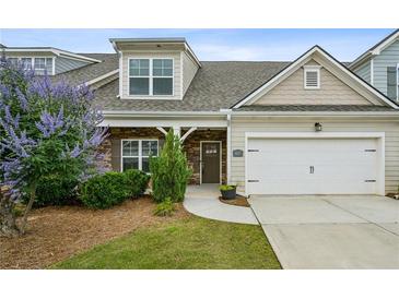 Charming home featuring a two-car garage, stone accents, and a beautifully landscaped front yard at 1637 Short Shadow Ln, Snellville, GA 30078
