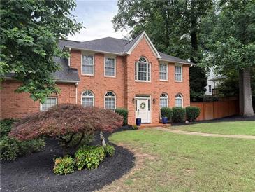 Charming two-story red brick home with a beautifully landscaped front yard and a welcoming front door at 200 Creek Run Ct, Alpharetta, GA 30005