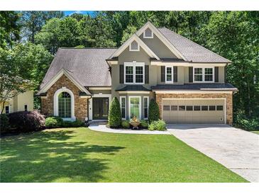 Charming two-story home featuring a stone and stucco facade, well-manicured lawn, and an attached two-car garage at 77 Skyland Dr, Roswell, GA 30075