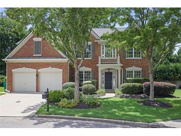 Traditional brick home featuring a two-car garage, manicured lawn, and mature trees at 2023 Belridge Se Ct, Smyrna, GA 30080