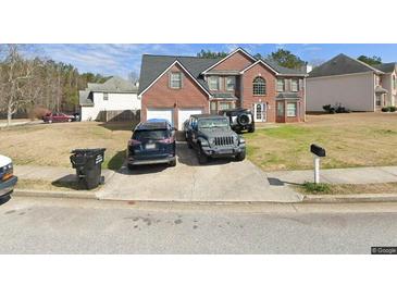 Two-story brick home featuring a two-car garage and a well-manicured front lawn at 696 Tomahawk Pl, Austell, GA 30168