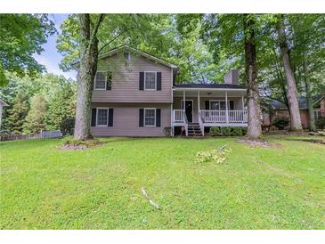 Charming two-story home with a covered front porch nestled among mature trees and a lush green lawn at 3110 Ashly Cove Ln, Snellville, GA 30078