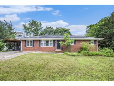 Charming one-story brick home with a well-maintained front yard and a carport, under a partly cloudy blue sky at 734 Meadowlark Dr, Villa Rica, GA 30180