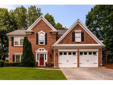 Charming two-story brick home featuring a well-maintained lawn, two-car garage and inviting red front door at 1767 Tidewell Trce, Lawrenceville, GA 30043