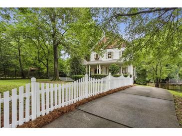 Charming two-story home with a white picket fence and lush landscaping, creating a welcoming curb appeal at 2177 Mauldin Nw St, Atlanta, GA 30318