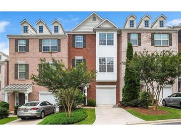 Charming brick townhome with dormer windows, manicured landscaping, and a private drive at 7863 Kiverton Pl, Atlanta, GA 30350